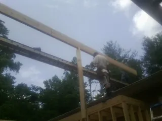Carpenter setting a ridge beam over a new addition frame — Ice Dam Removal by Roofing Brothers in Cost