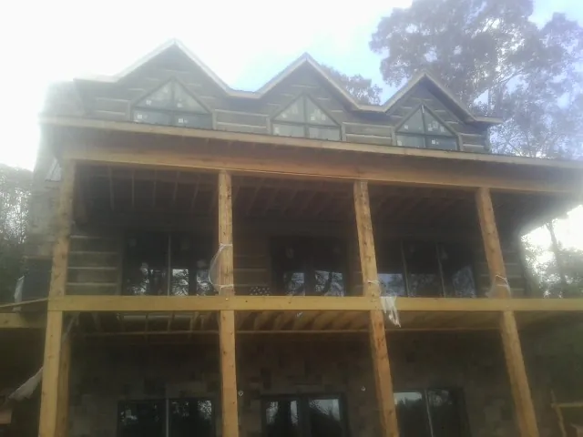 Dormers and porch framing on a large log home under construction — Roof Coating work by our crew in Cost